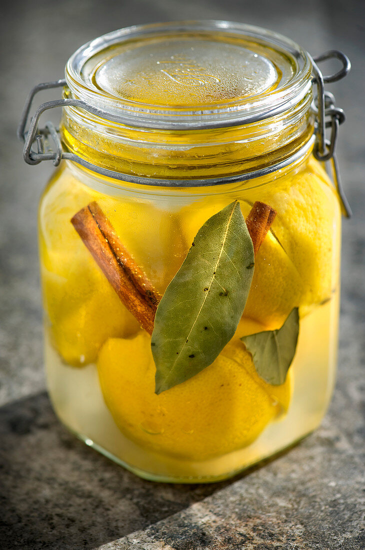 Preserved Moroccan salted lemons with cinnamon and bay leaves in a flip-top jar