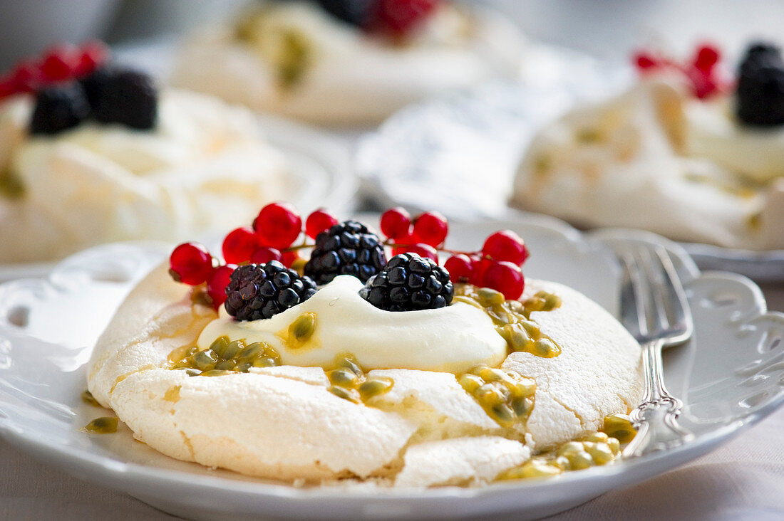 Mini pavlovas with blackberries, redcurrants and passion fruit