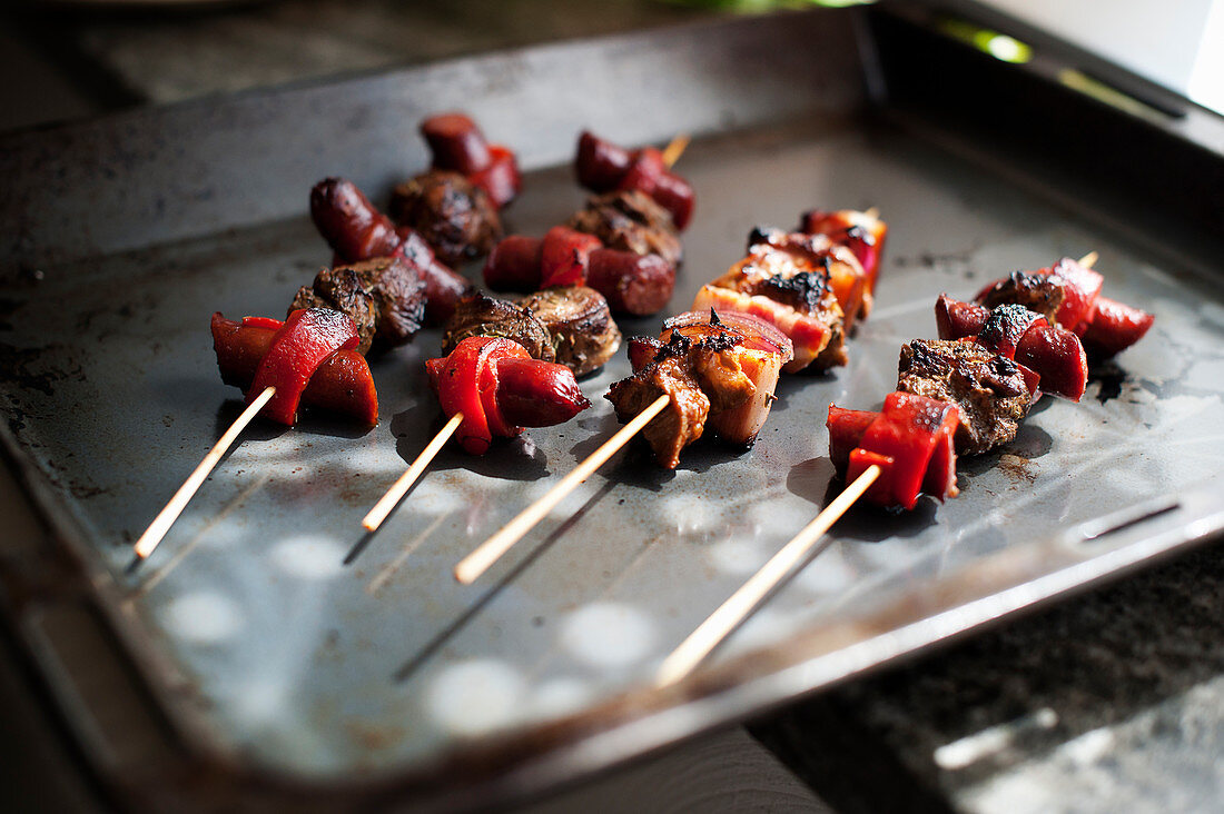 Lamb skewers with Merguez and grilled peppers on a baking tray