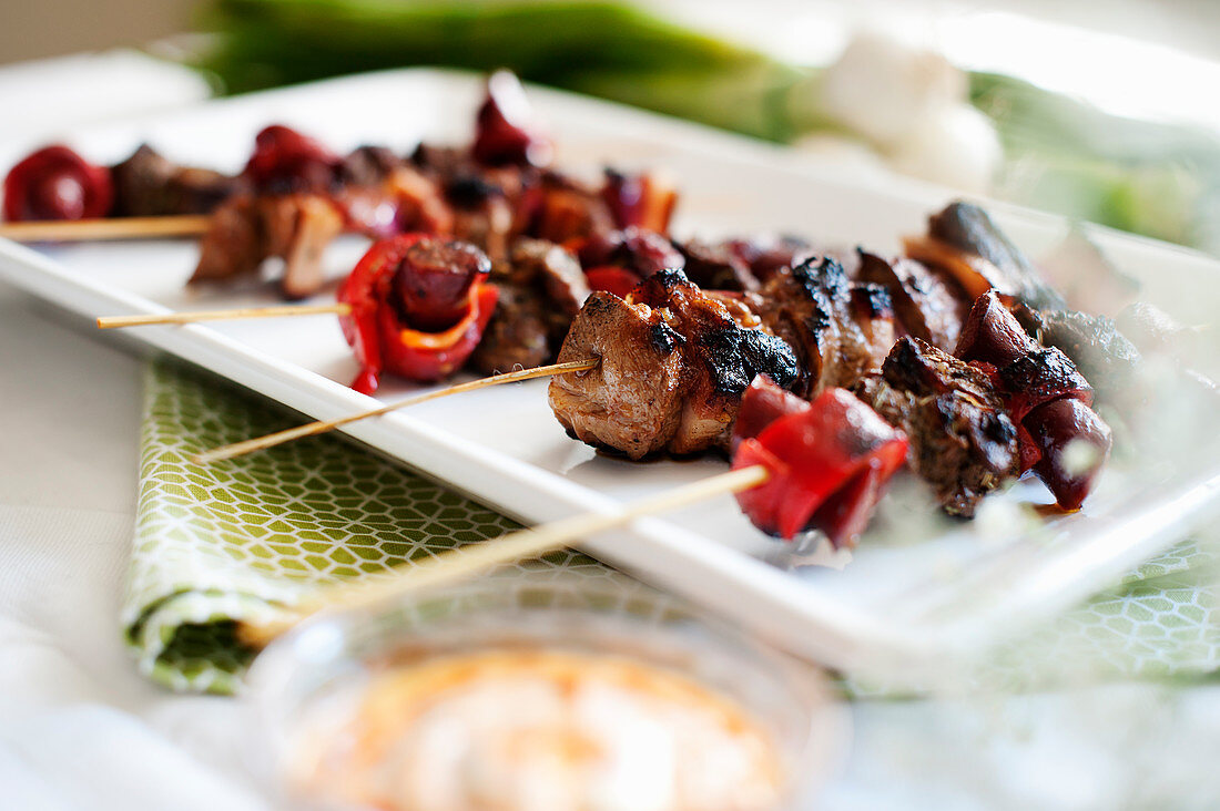 Lammspieße mit Merguez und Grillpaprika auf Servierplatte