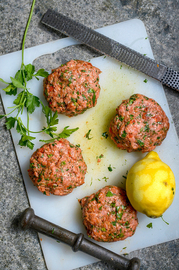 Raw lamb meatballs and lemon on a chopping board