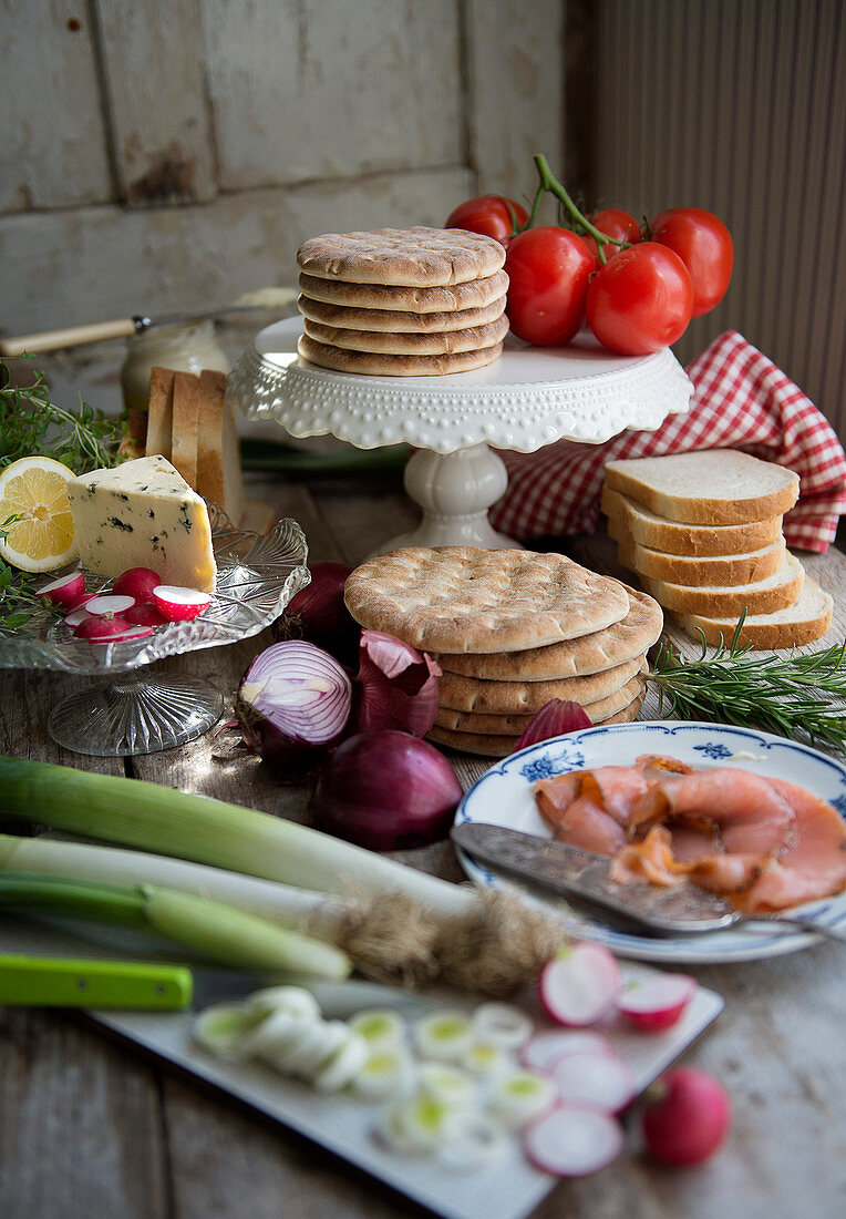 A buffet with the ingredients for Smorgastarta: flatbread, toast, smoked salmon, cheese and vegetables