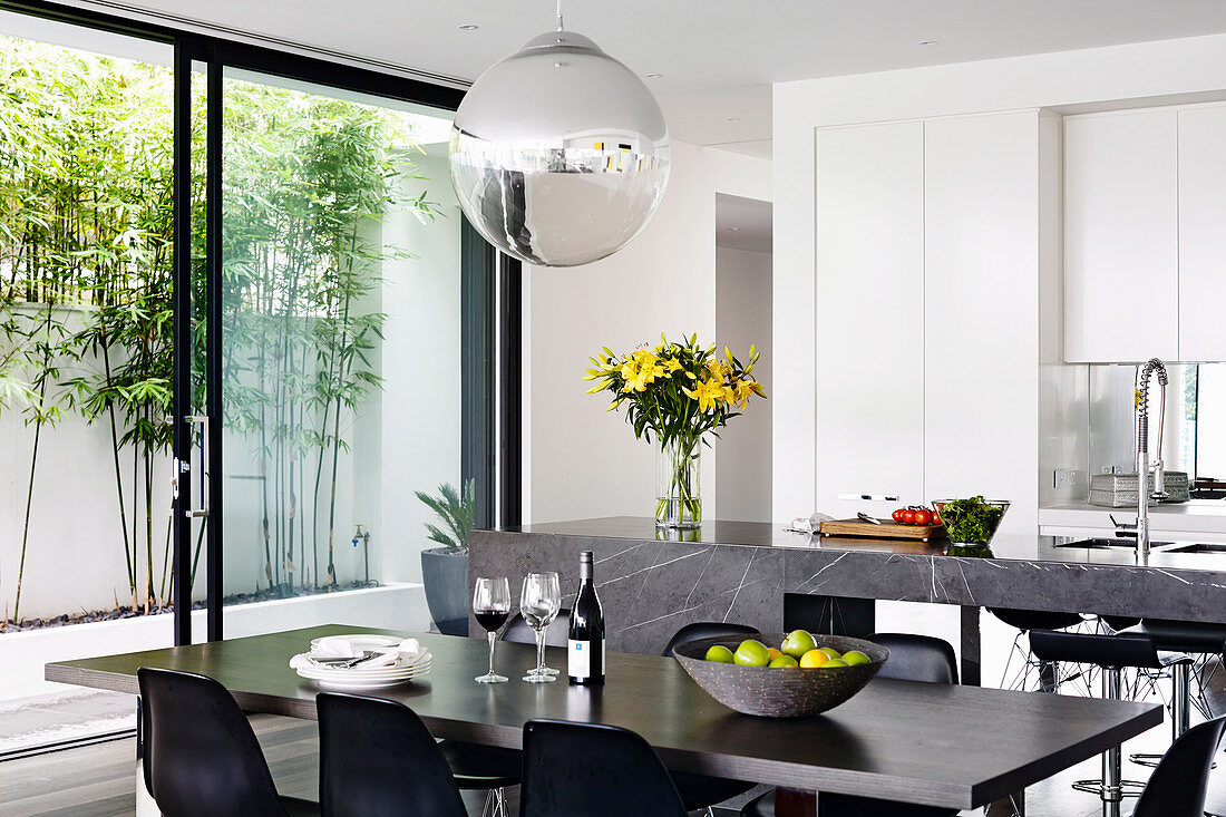 Dining table in front of the modern open kitchen with patio door