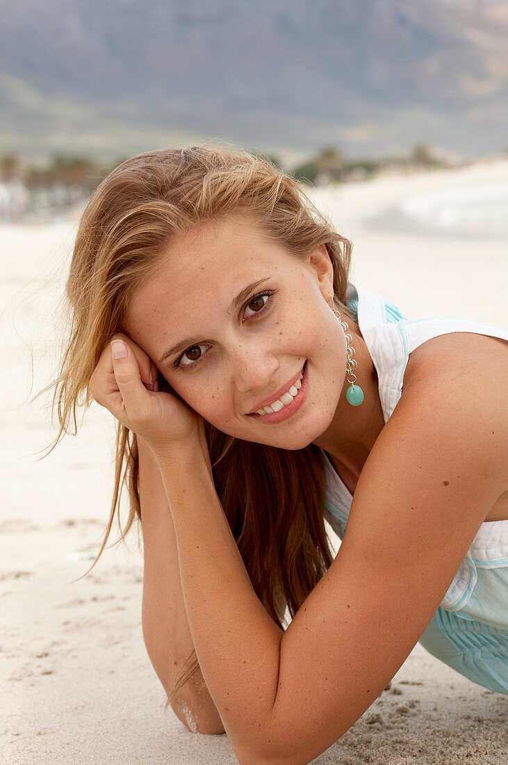 A young blonde woman on a beach wearing a light-blue top
