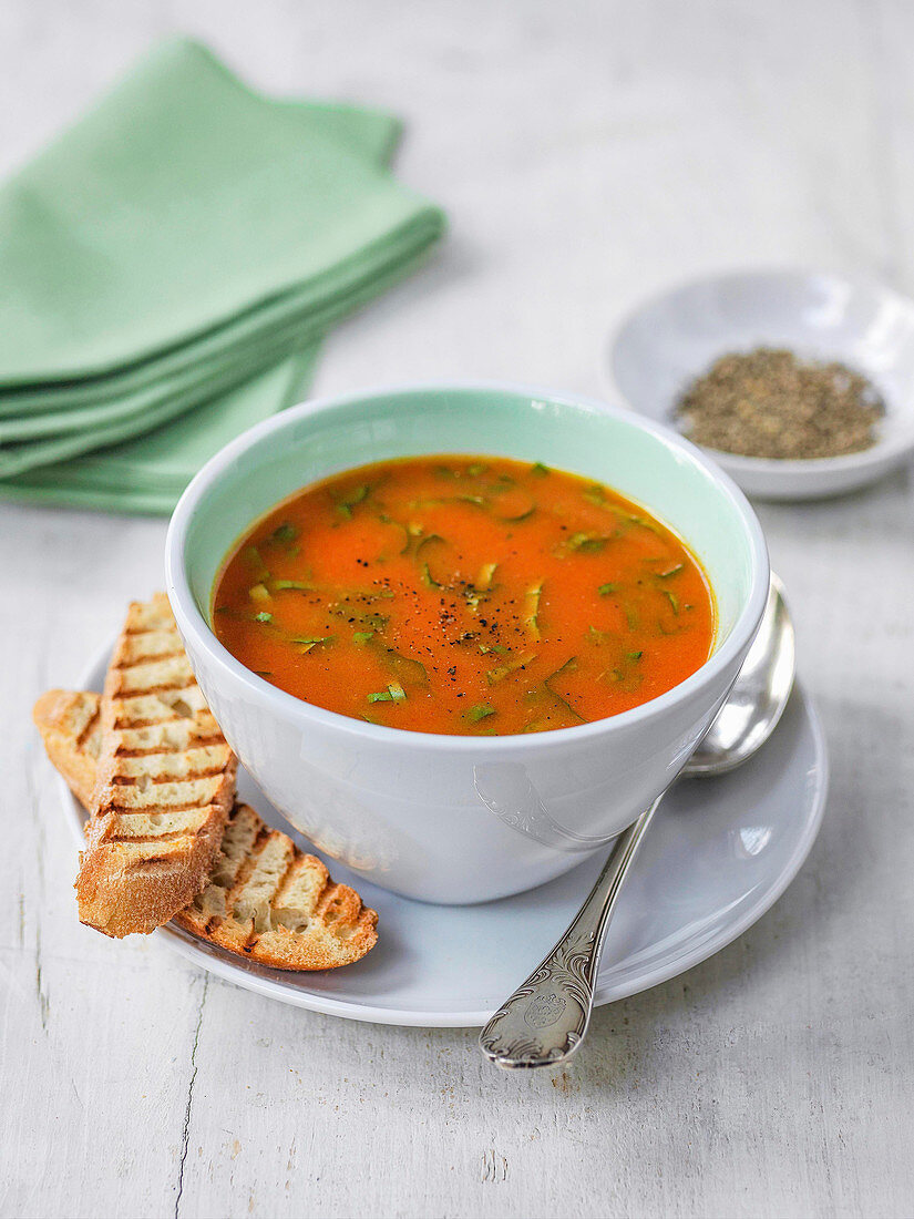 Tomato soup garnished with herbs, grilled ciabata bread and ground black pepper