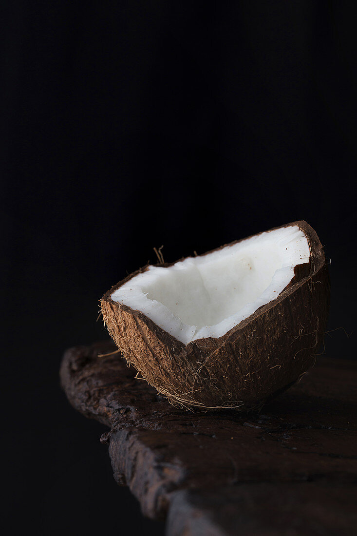 Close-up of ripe aromatic coconut half on rough wooden table