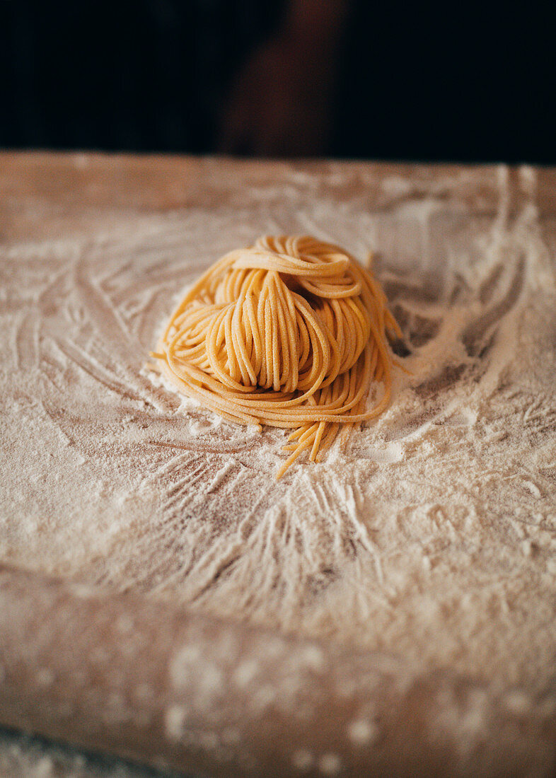 Selbst gemachte Spaghetti auf bemehltem Holzbrett