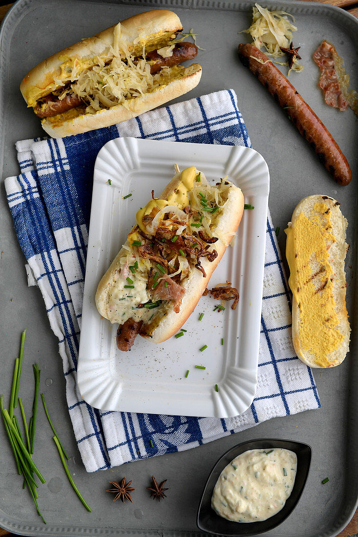 Hot Dog mit Bratwurst, Speck, Kraut und karamellisierten Zwiebeln