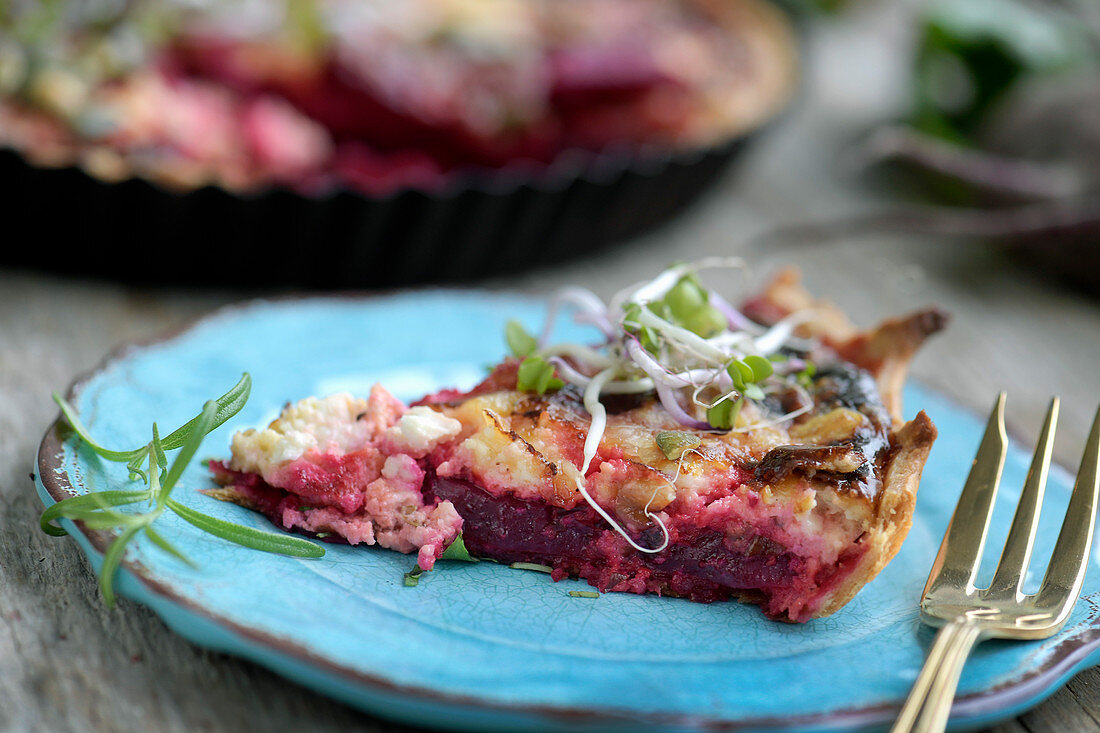 A slice of beetroot quiche with feta cheese on a plate