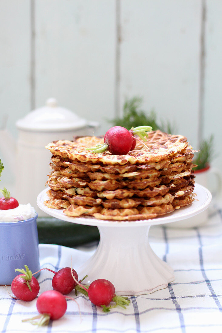 A stack of waffles on a pastry stand, served with radishes and a quark dip