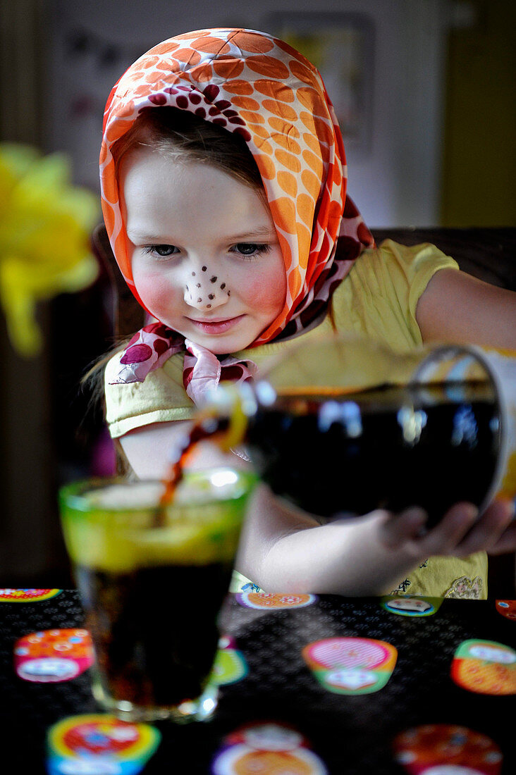 Mädchen in Osterhasenverkleidung giesst Cola in ein Glas