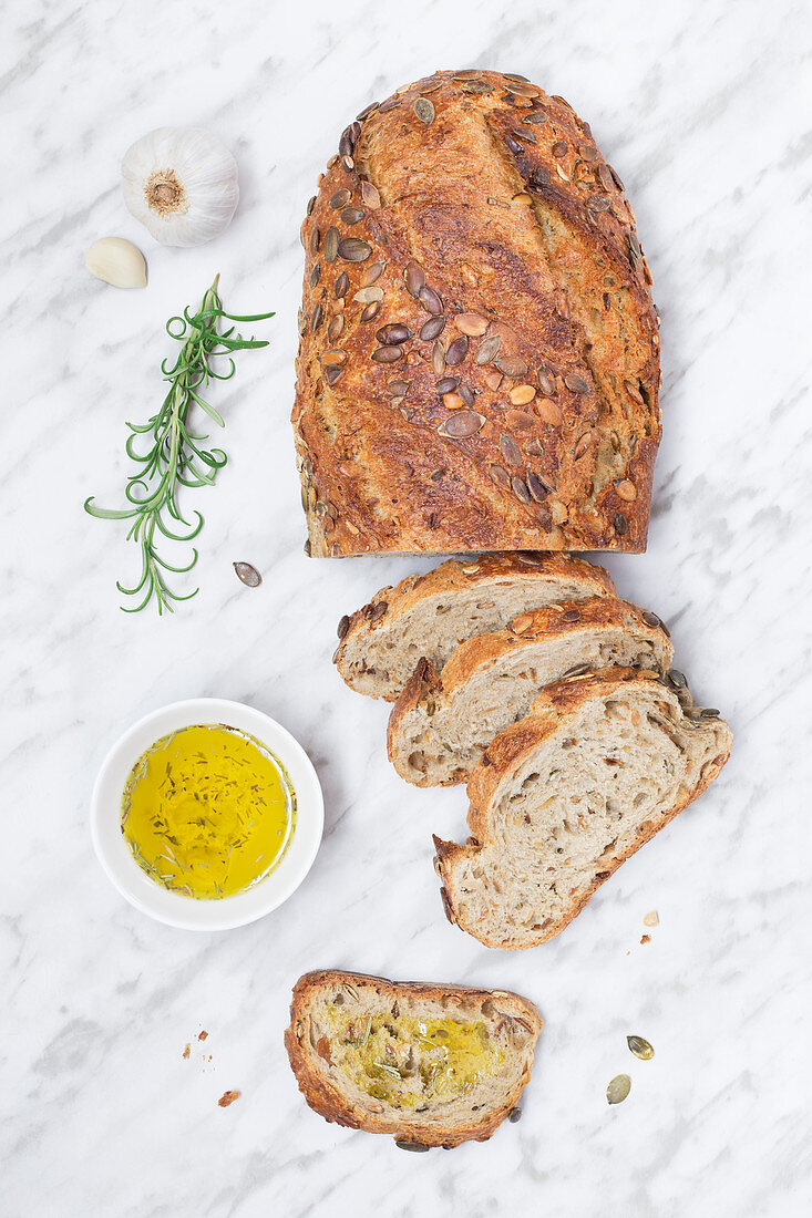 Frisch gebackener Brotlaib mit Samen und Schälchen Olivenöl