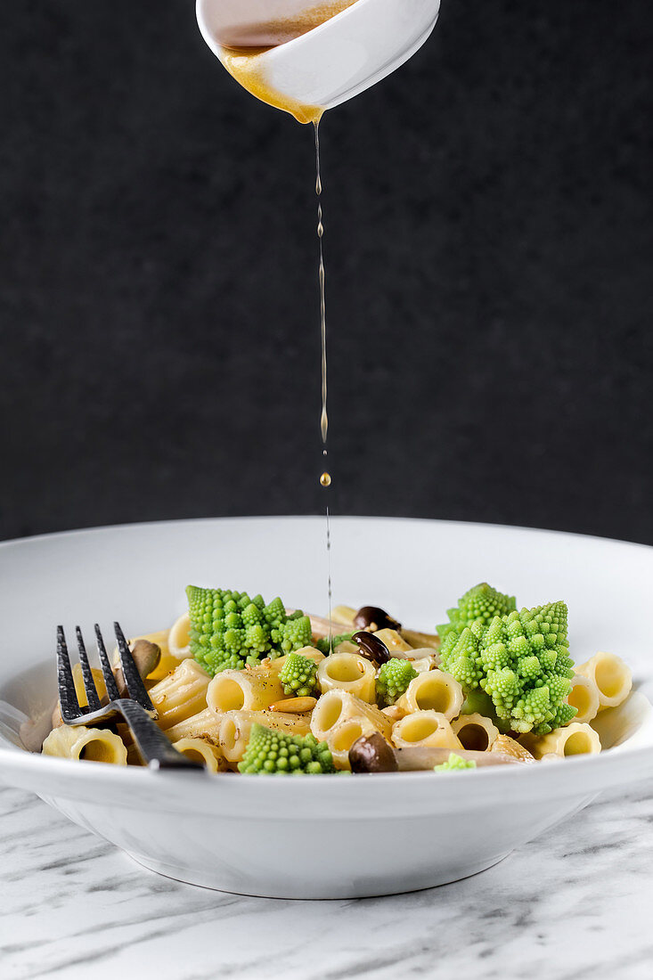 Sauce pouring to appetizing pasta with romanesco cauliflower