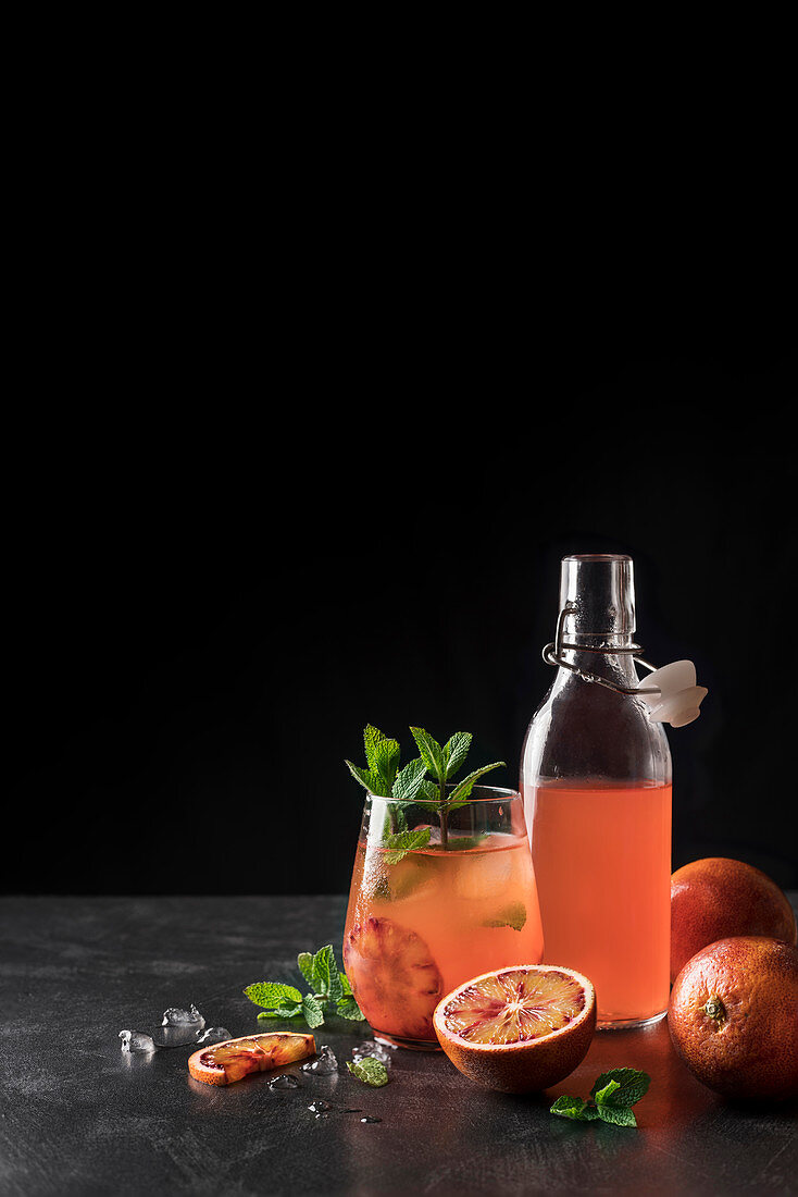 Jug and bottle filled with refreshing lemonade made of red oranges