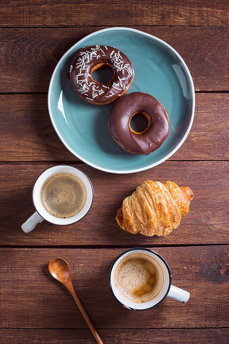 Zwei Becher Kaffee, Croissant und Donuts