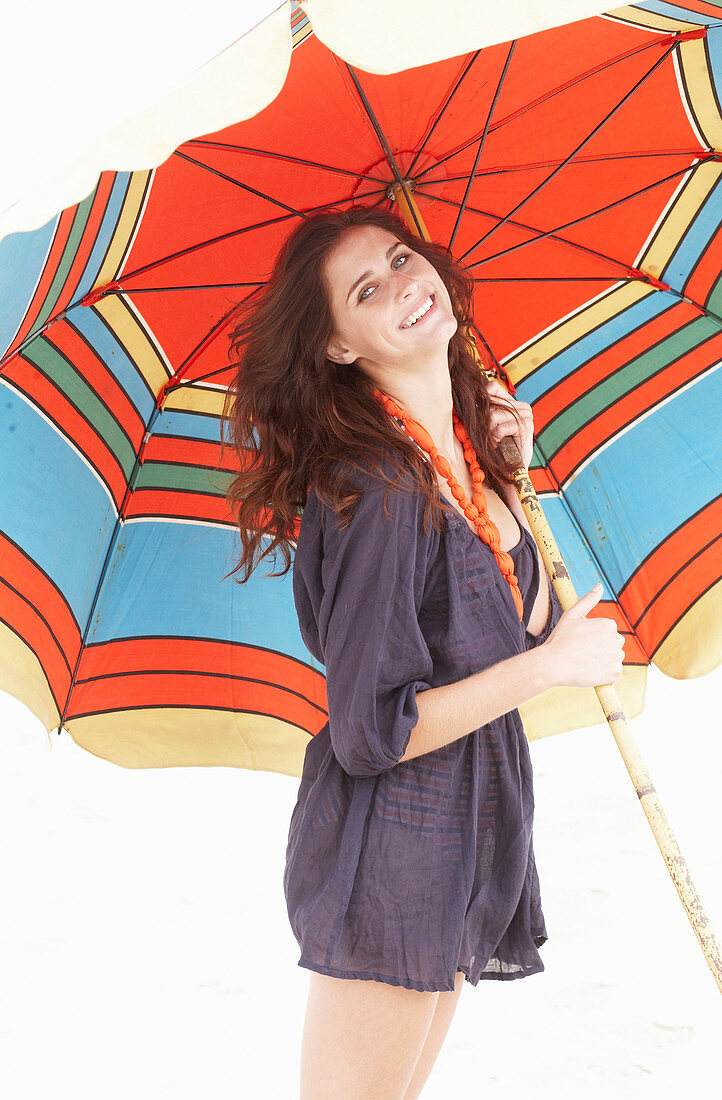 A brunette woman wearing a purple bath robe with a colourful parasol