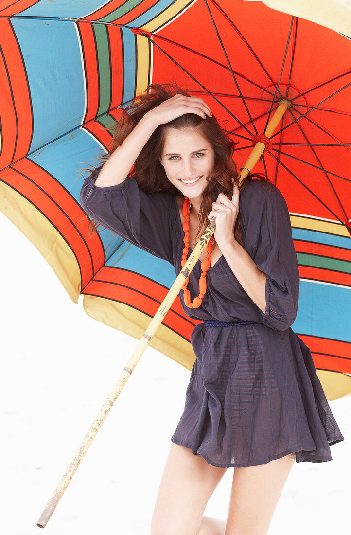 A brunette woman wearing a purple bath robe with a colourful parasol