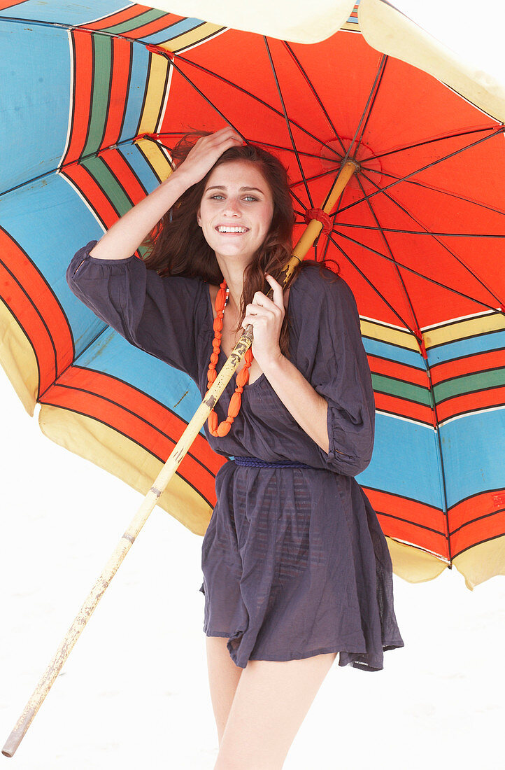 A brunette woman wearing a purple bath robe with a colourful parasol