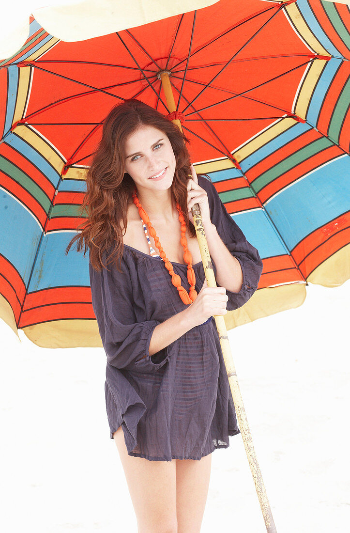 A brunette woman wearing a purple bath robe with a colourful parasol