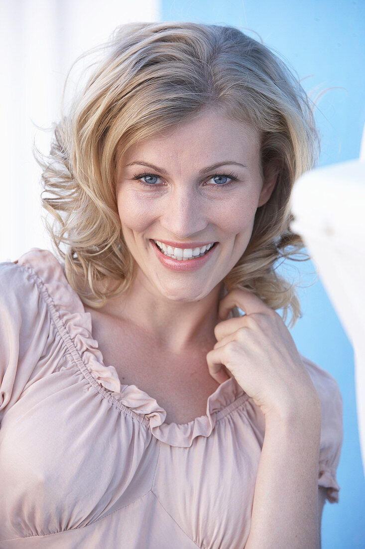 A blonde woman wearing a pink short-sleeved blouse