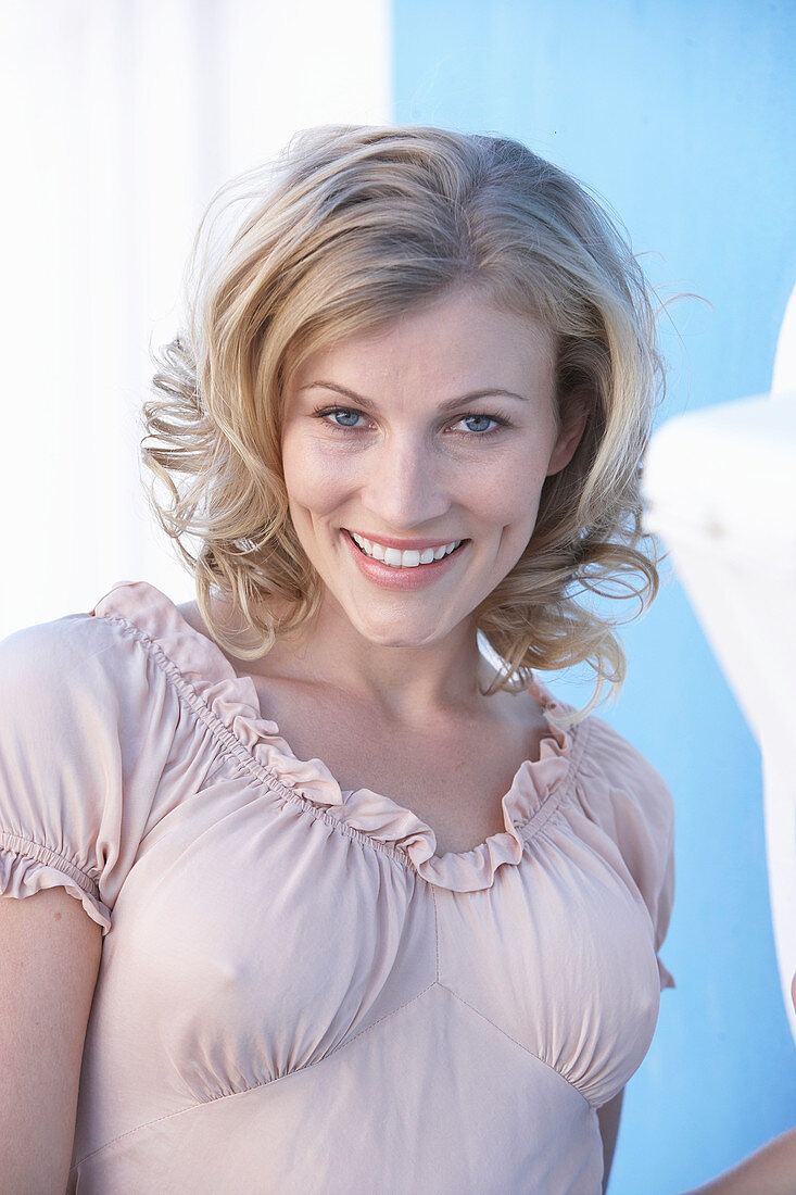 A blonde woman wearing a pink short-sleeved blouse