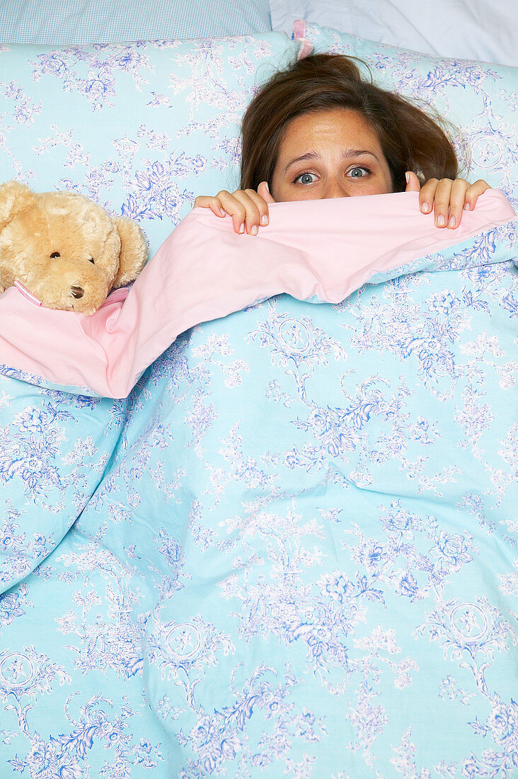 A young girl hiding under the bedclothes