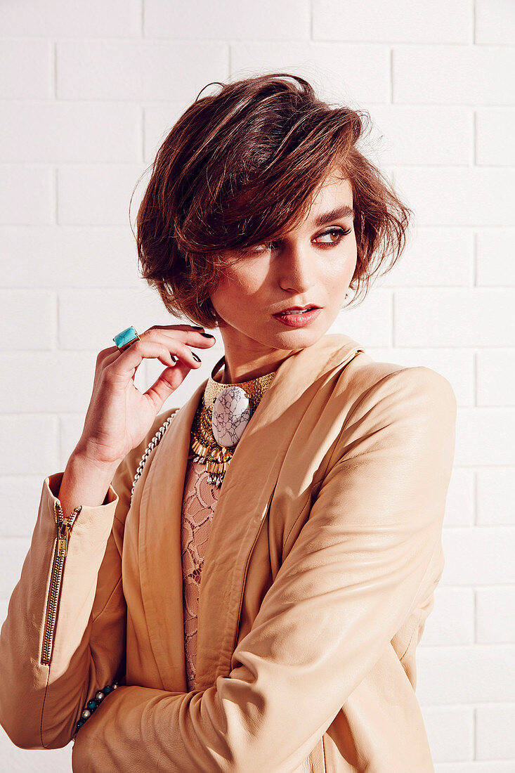 A young woman wearing a brown leather jacket with fashionable jewellery