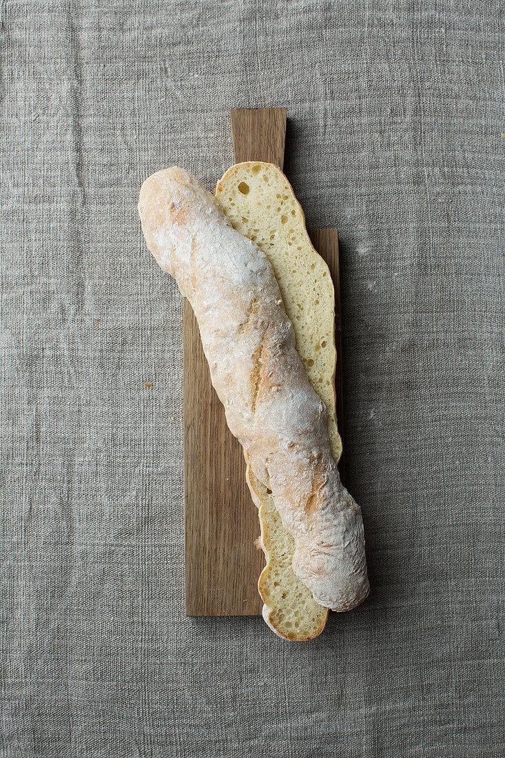 A light baguette, halved lengthways, on a wooden board