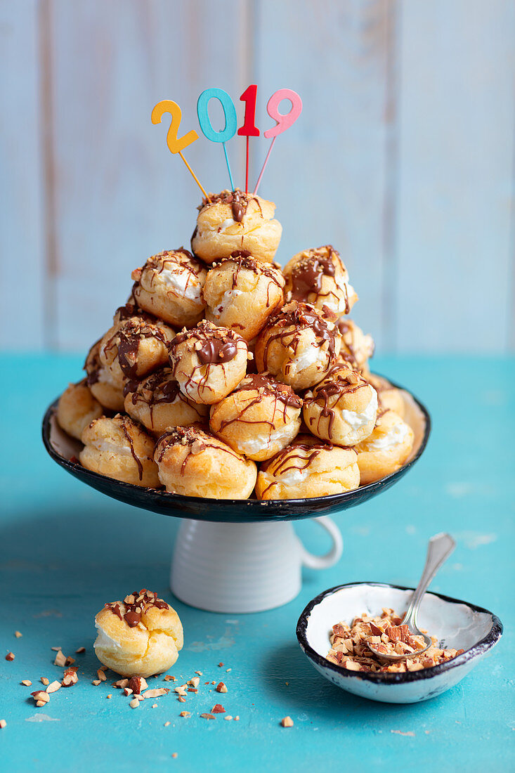 Profiterol with whipped cream, chocolate and almonds for new year
