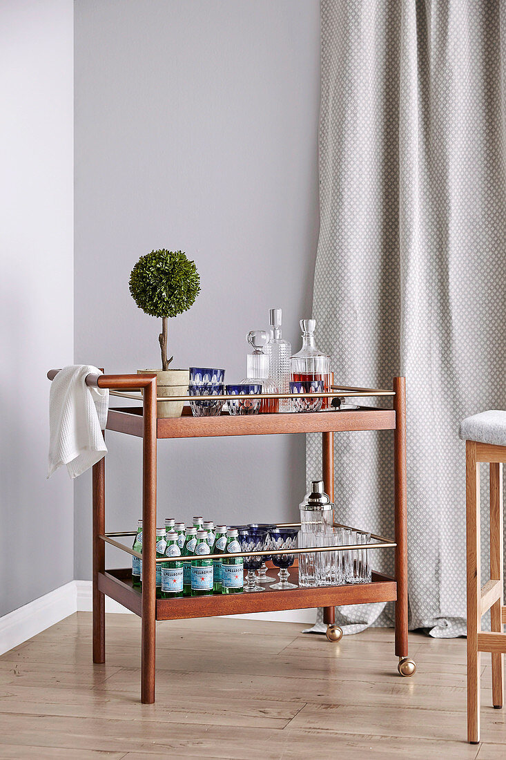 Simple serving trolley with drinks in front of a grey wall
