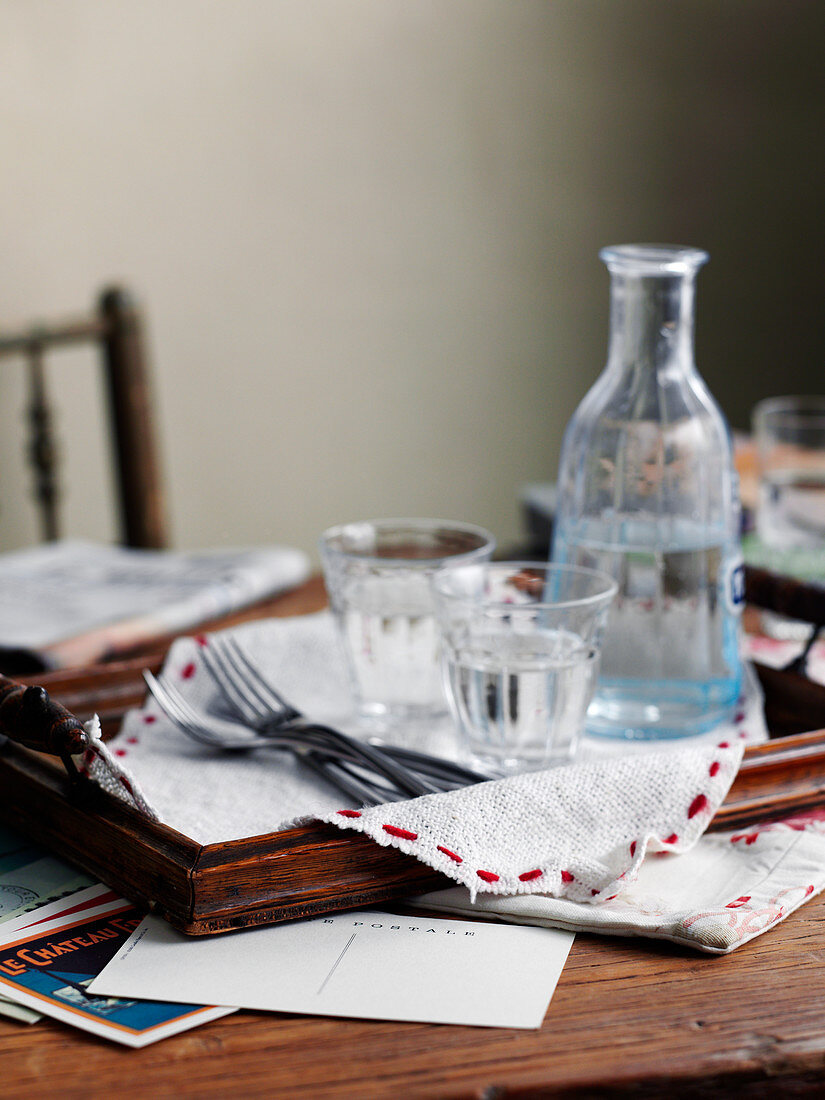 A carafe of water and water glasses on a wooden tray on a desk
