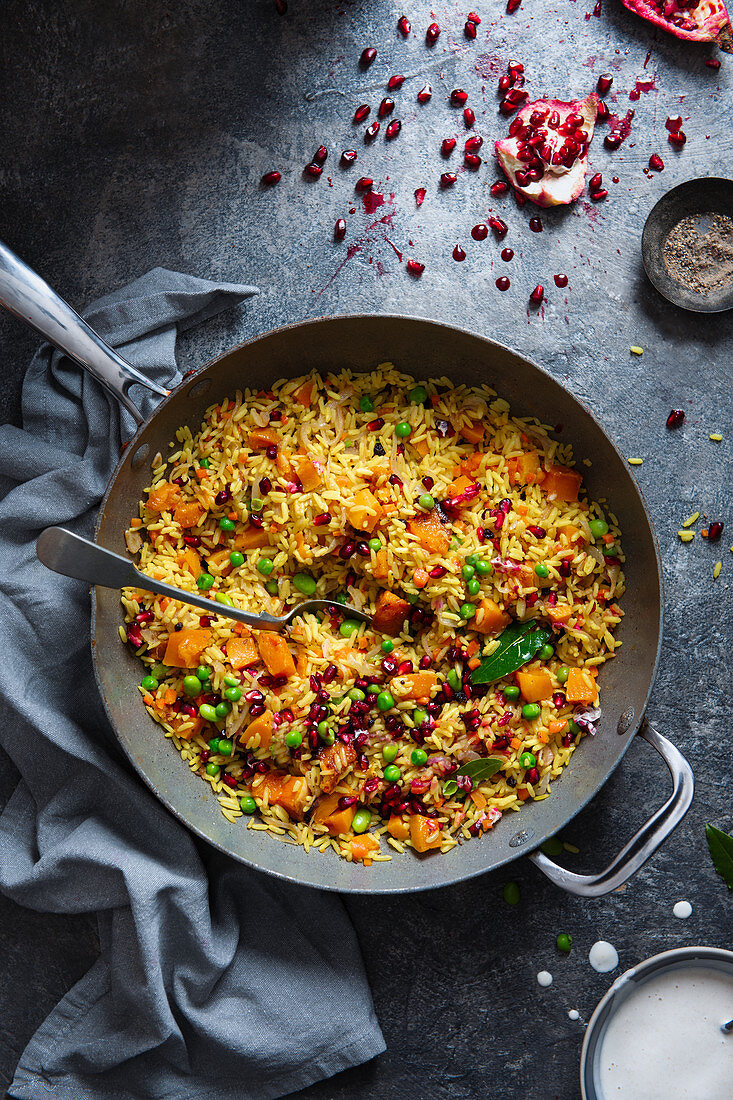 Vegeterian dish of pilaf rice with roasted butternut squash, peas, spices (cumin, tumeric) and pomegranate