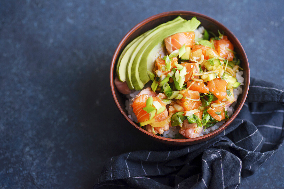Poke bowl with raw marinated salmon, cucumbers and avocado