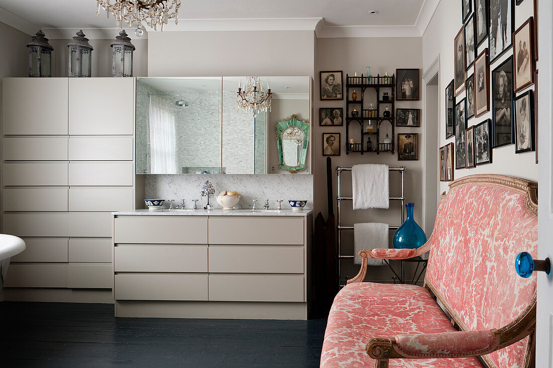 Handmade units in bathroom with old family photographs and French settle reupholstered in vintage toile de jouy