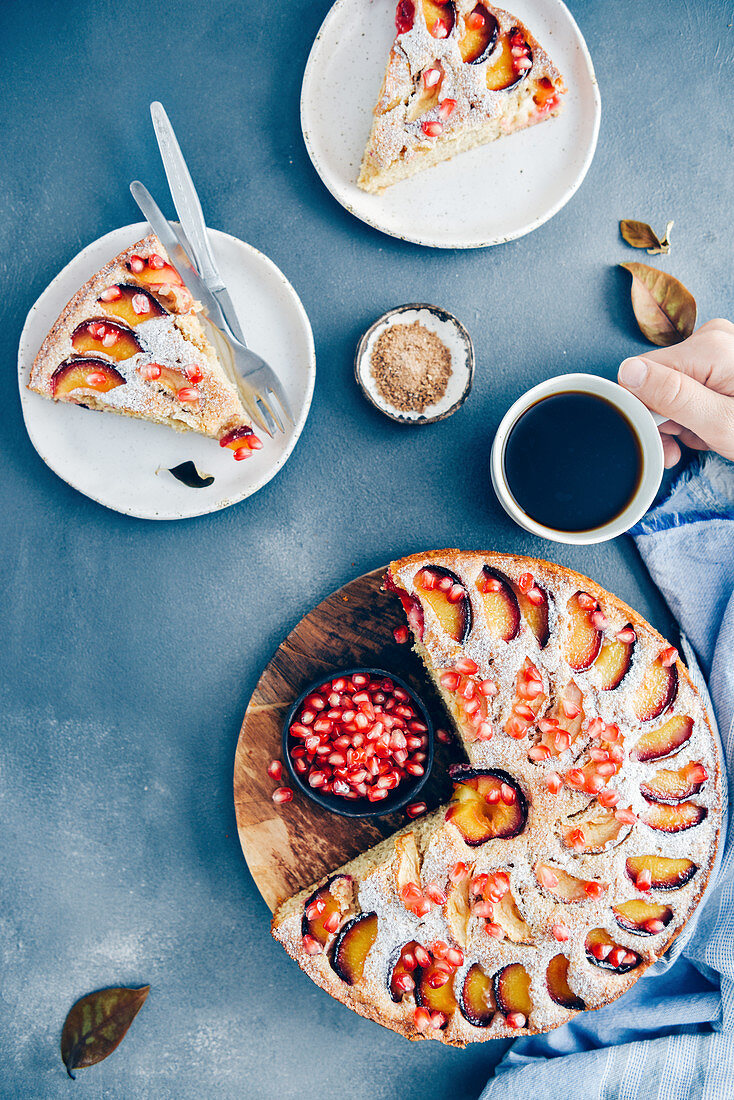 Apfel-Pflaumenkuchen mit Granatapfelkernen, angeschnitten zum Kaffee