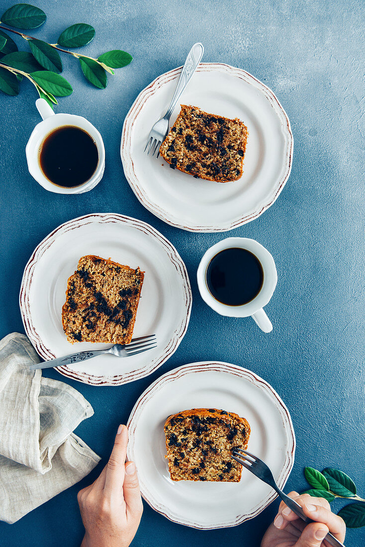 Hands ready to eat a slice of chocolate chip banana bread on a white plate