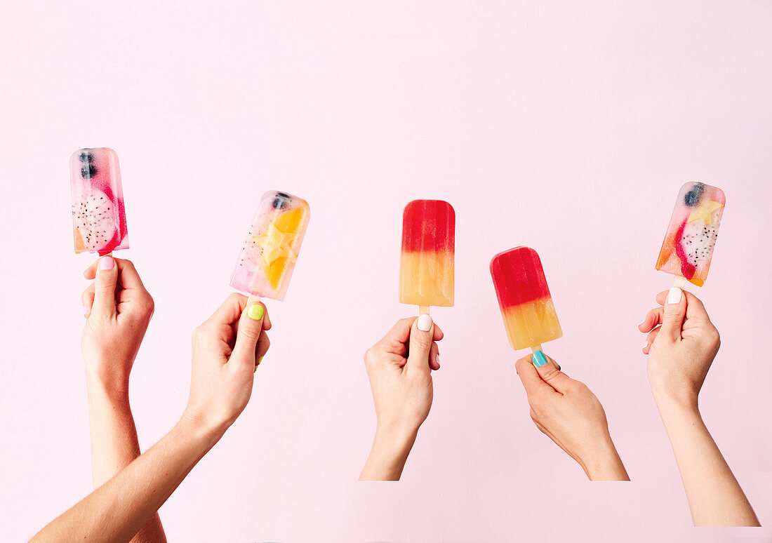 Hands holding exotic fruit ice popsicles