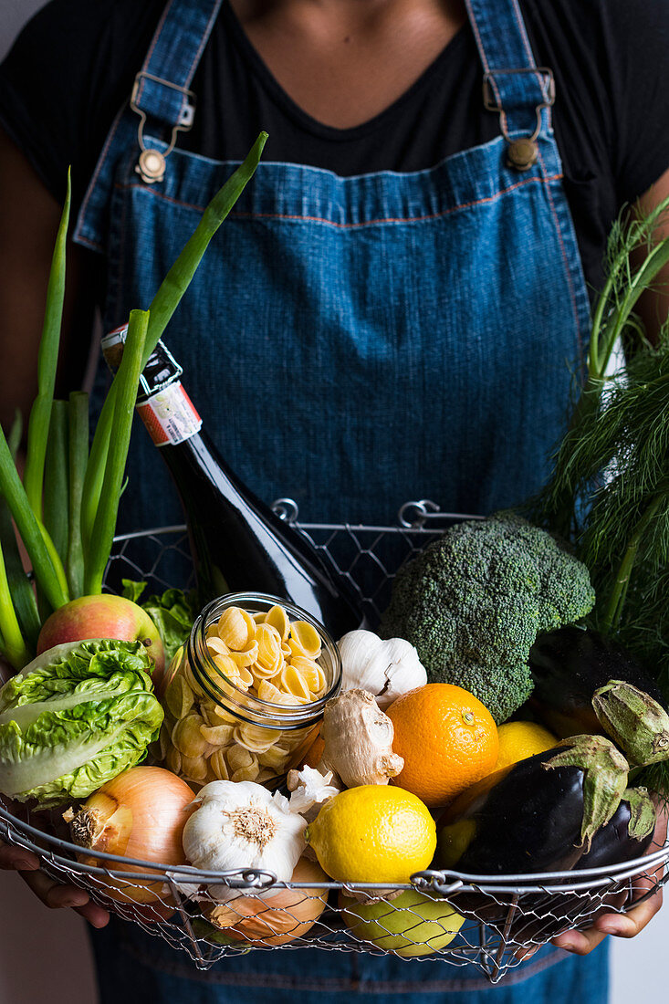 Frau hält Drahtkorb mit frischem Gemüse, Obst und Lebensmitteln