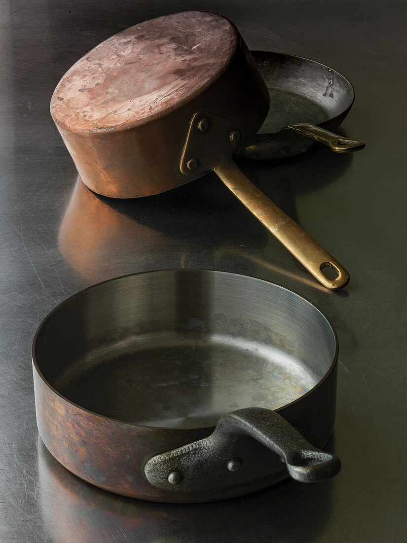 Old copper pans on stainless steel surface