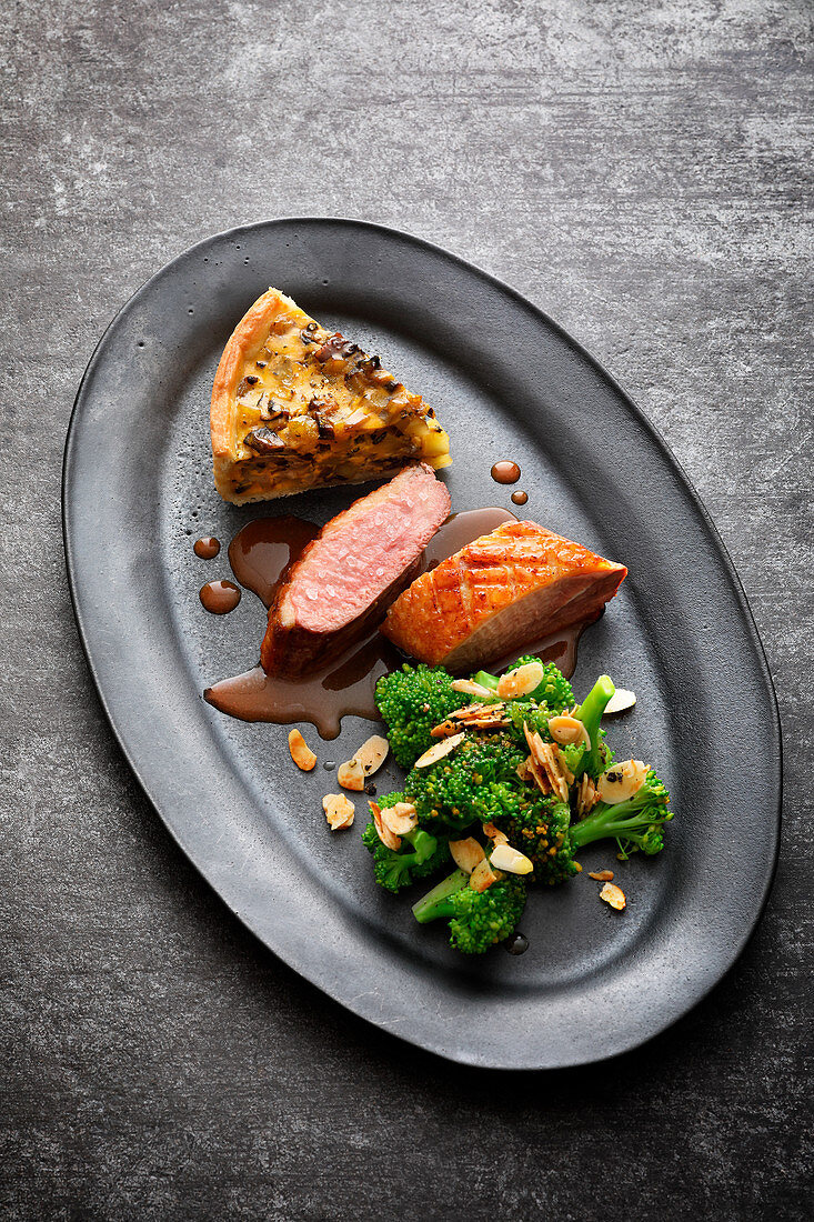 Duck breast with a slice of potato and pumpkin tart, and almond-broccoli