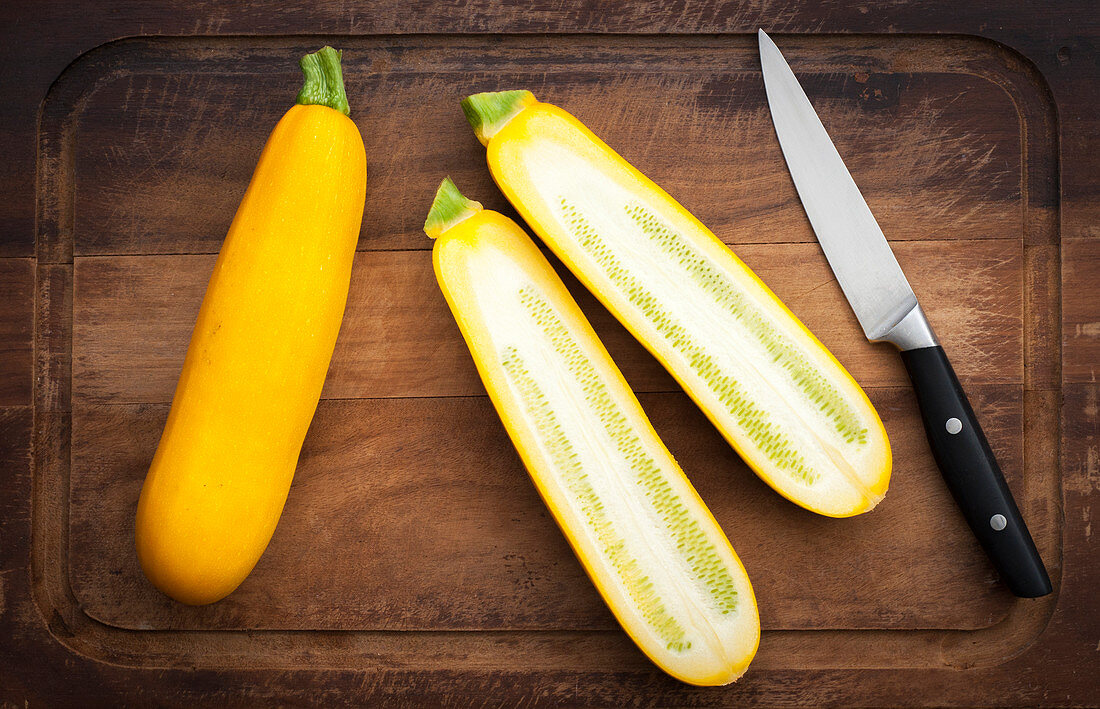 Zwei gelbe Zucchini, einmal ganz und einmal halbiert