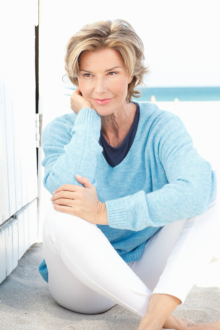 A mature woman wearing a blue jumper and white trousers