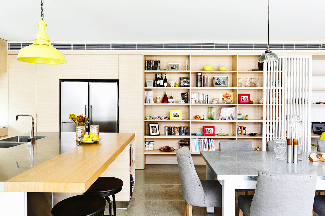 Kitchen counter and dining area with gray upholstered chairs in front of an open shelf