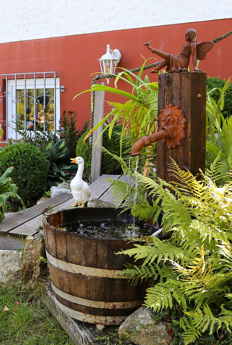 Fountain made from waterspout and wooden tub in garden