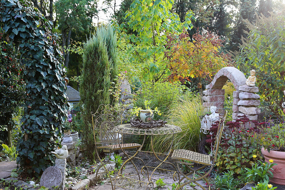 Seating area in autumnal garden with romantic metal furniture