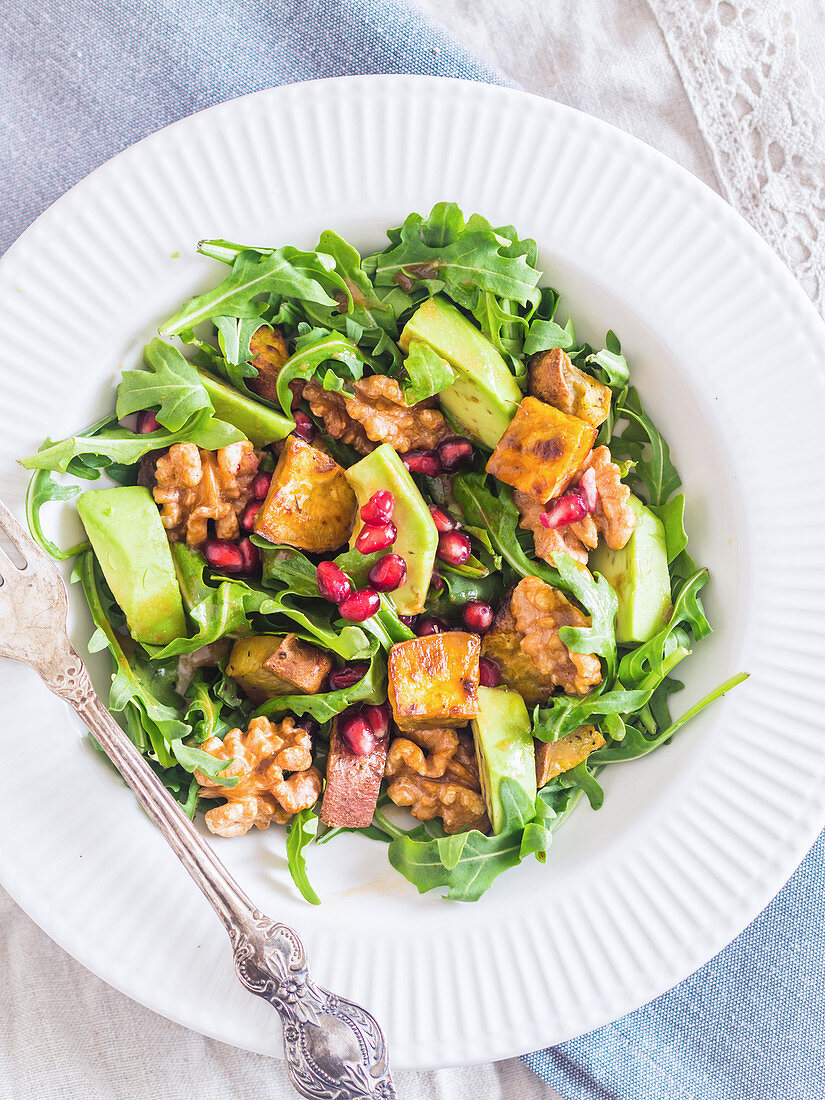 Arugula salad with sweet potatoes, avocado, pomegranate and grilled nuts