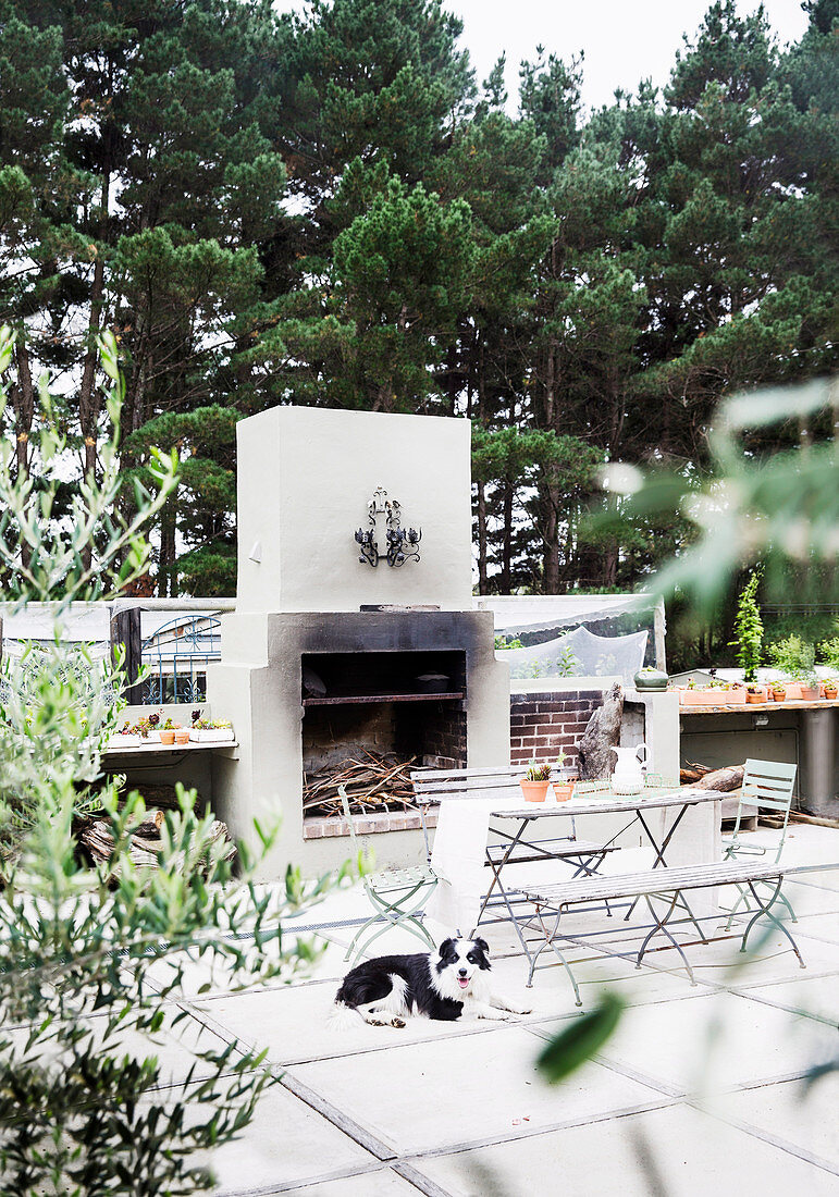 Garden table with bench and chairs in front of the grill on the terrace