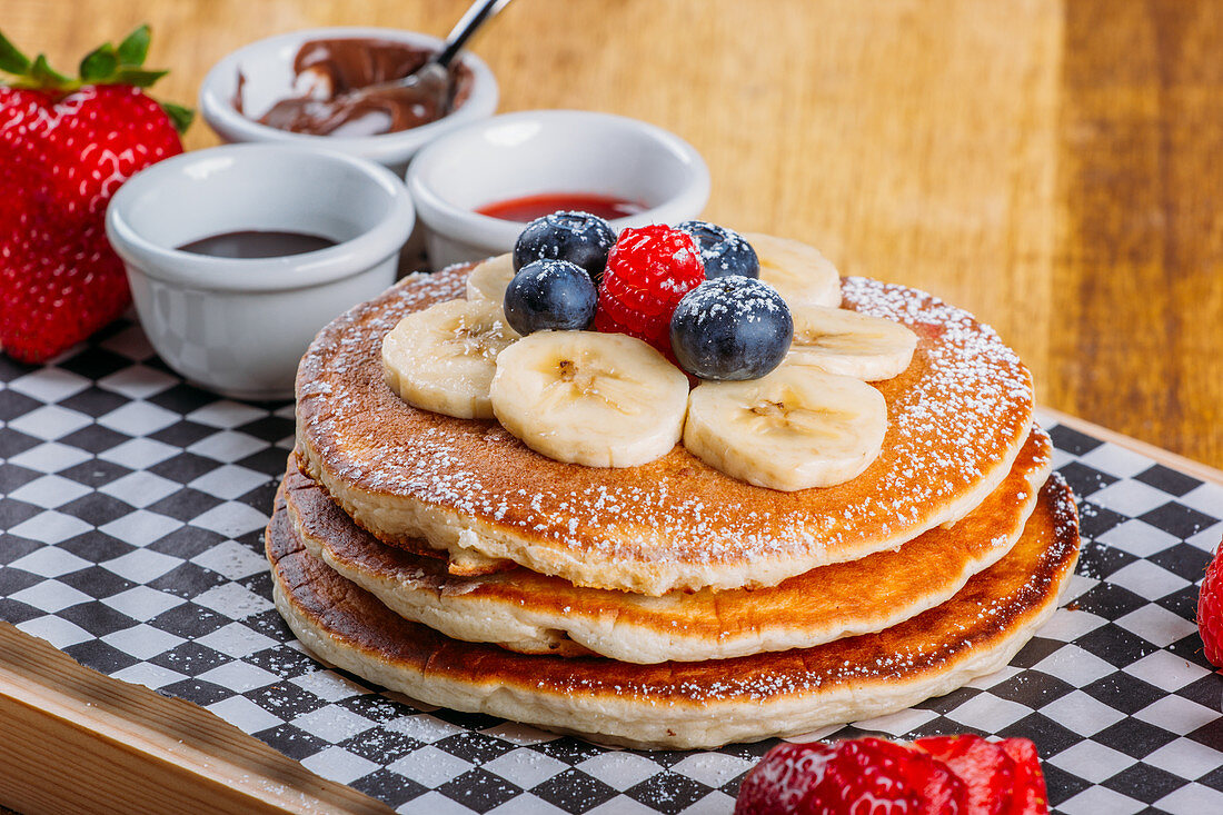 Delicious fried fluffy pancakes with icing sugar and fresh berries served for breakfast