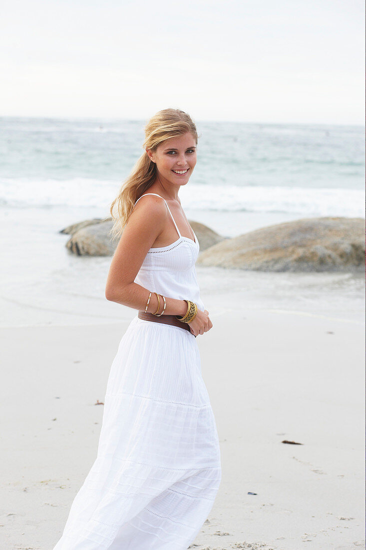 Blond Frau in weißem Sommerkleid am Meer