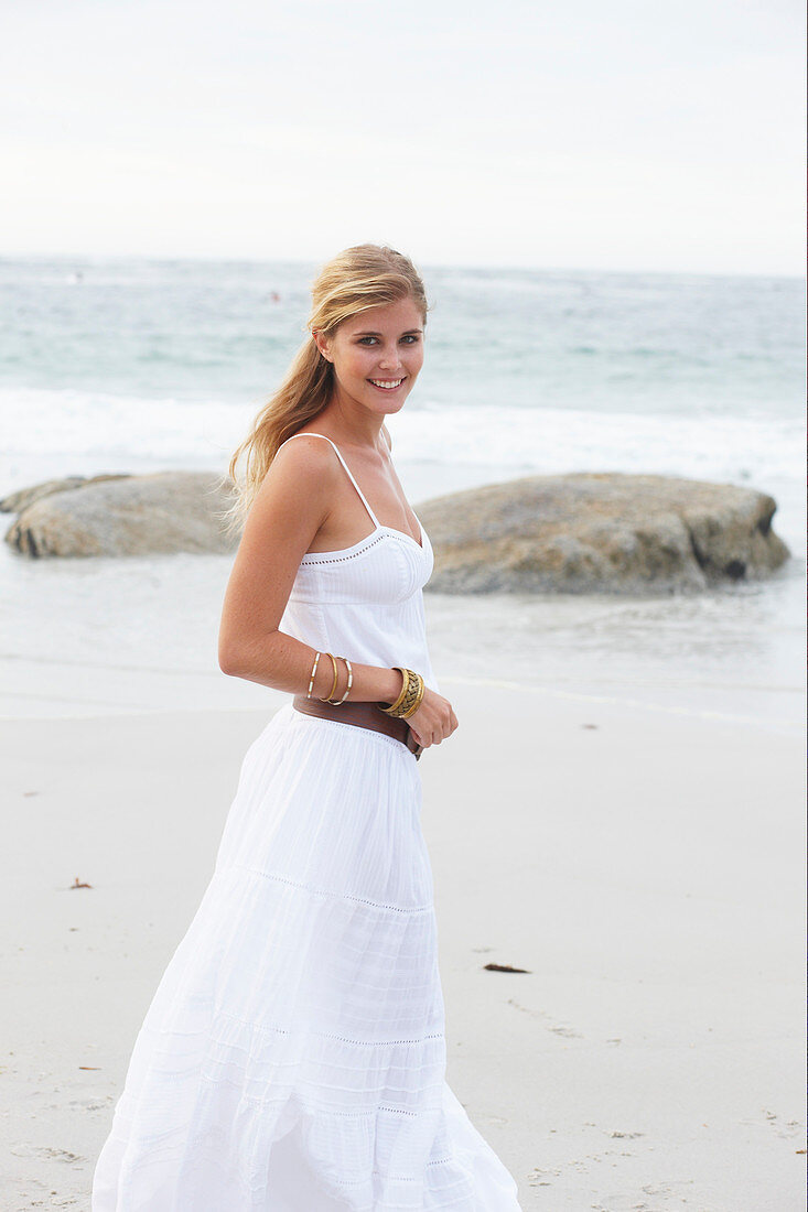 Blond Frau in weißem Sommerkleid am Meer